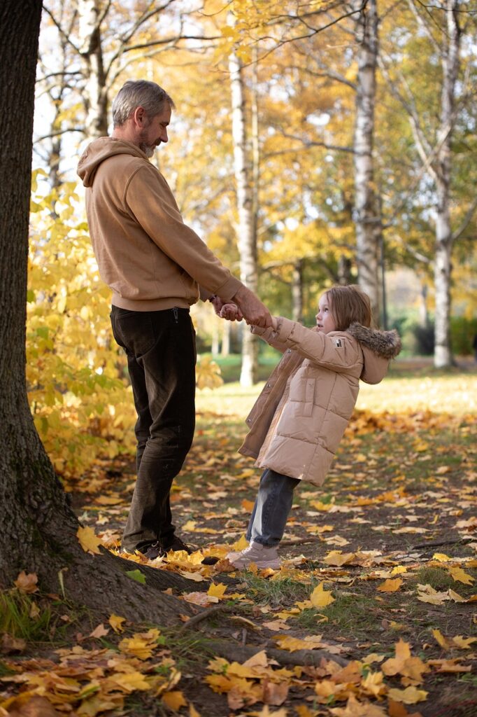 Father sharing a precious moment with his daughter under a tree in the fall while contemplating his term life insurance in Portage